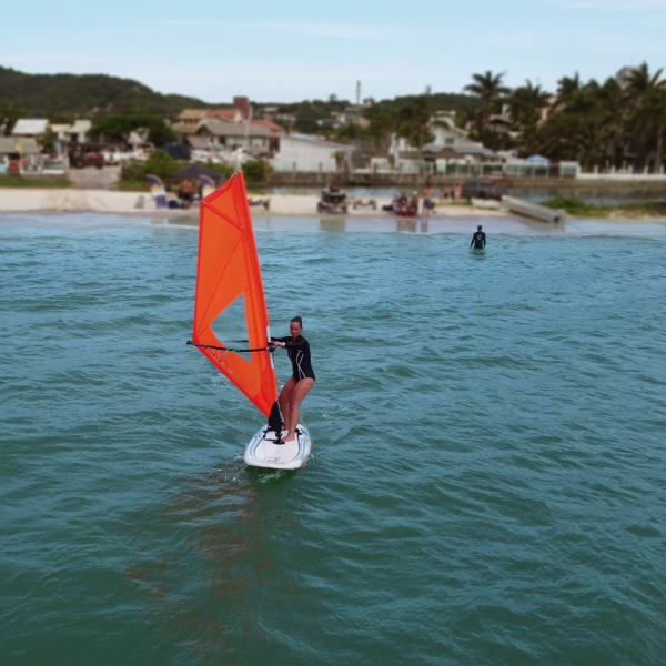 Aula de windsurf ao pôr do sol com mar calmo e atmosfera mágica em Florianópolis.