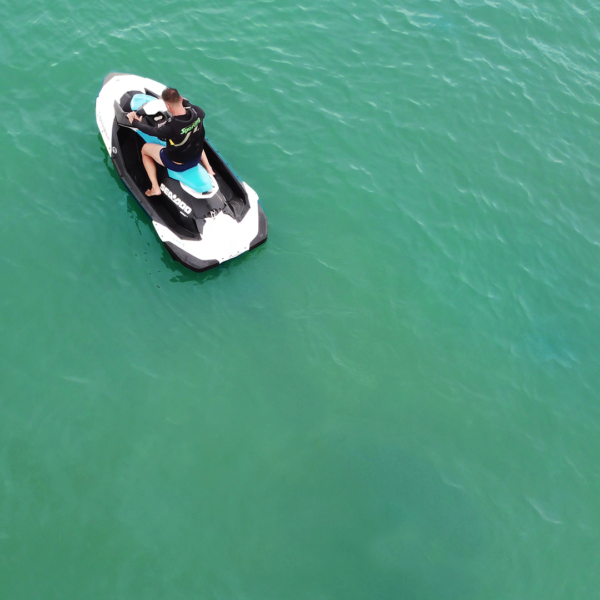 Instrutor explicando uso do jetski com colete e equipamento de segurança antes do passeio em Florianópolis.