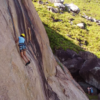 Pessoa praticando escalada em rocha natural com visual panorâmico em meio à natureza de Florianópolis.