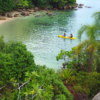 Casal remando até a Ilha do Francês em caiaque durante passeio romântico com parada para relax e fotos.