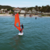 Aula de windsurf ao pôr do sol com mar calmo e atmosfera mágica em Florianópolis.